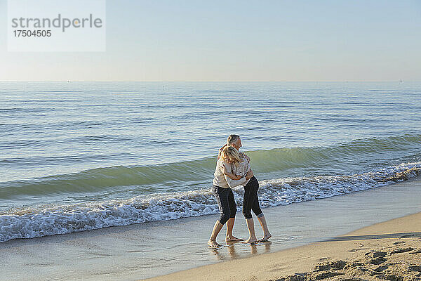 Verspieltes Paar genießt den Strand in der Nähe der Küste