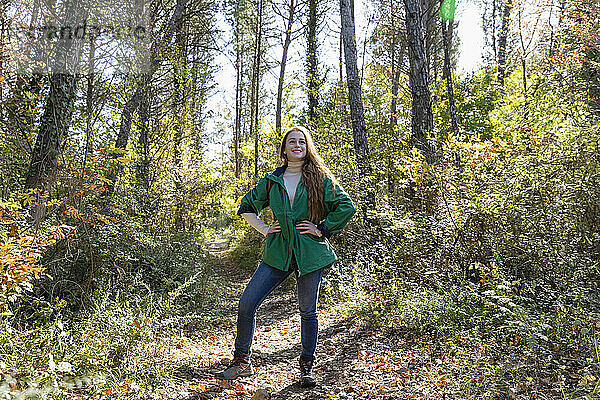 Junge Frau mit der Hand auf der Hüfte steht im Wald