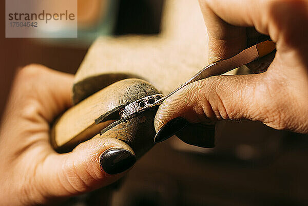 Weiblicher Juwelier schnitzt Ring mit Werkzeug in der Werkstatt