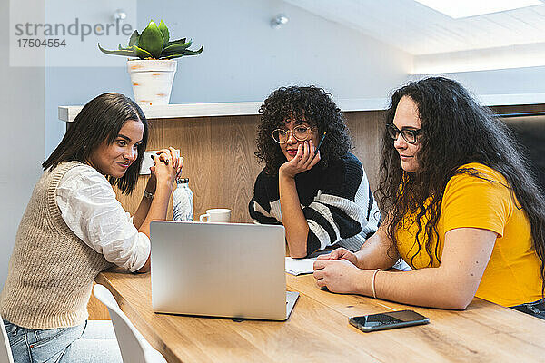 Junge Geschäftsfrauen schauen im Coworking-Büro auf Laptop