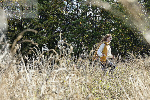 Fröhliche Frau läuft an einem sonnigen Tag im Gras