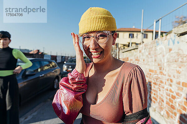 Glückliche Frau mit Strickmütze und Sonnenbrille auf Fußweg