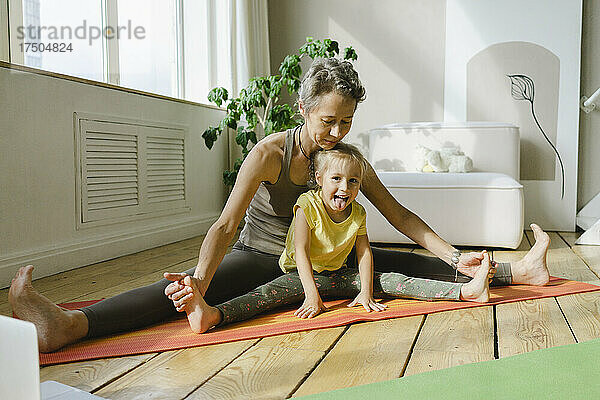 Mutter hilft Tochter beim Spagat der Beine auf der Trainingsmatte