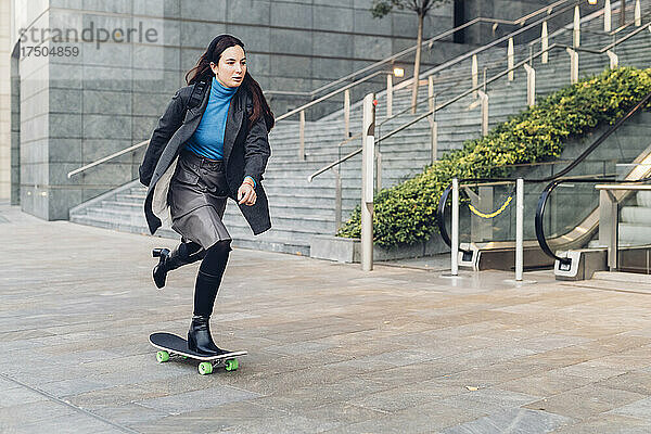 Geschäftsfrau fährt Skateboard am Bürogebäude vorbei