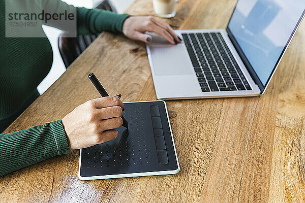 Freiberufler mit Laptop und Grafiktablett im Café