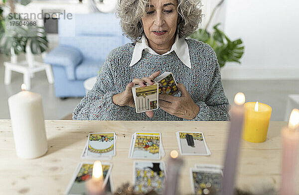 Ältere Frau liest zu Hause Tarotkarten auf dem Tisch