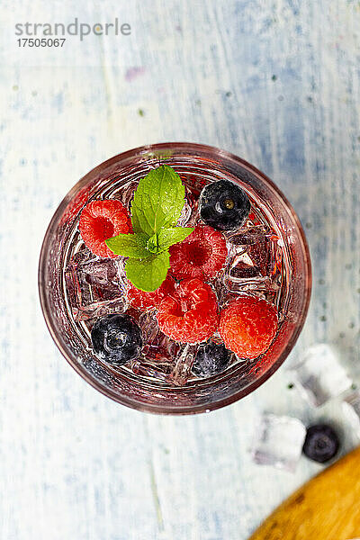 Glas Gin Tonic mit Minze  Eiswürfeln und rohen Beeren