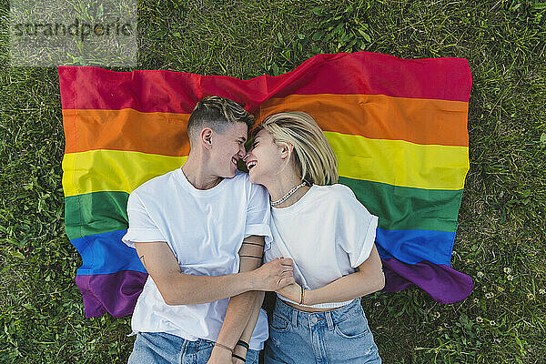 Glückliches romantisches junges Paar  das sich auf der Regenbogenfahne entspannt