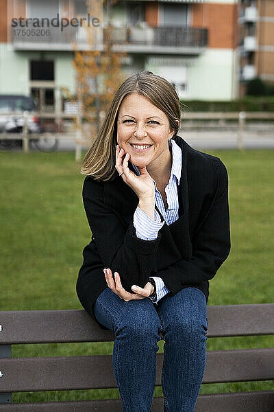 Lächelnde Frau sitzt auf einer Parkbank