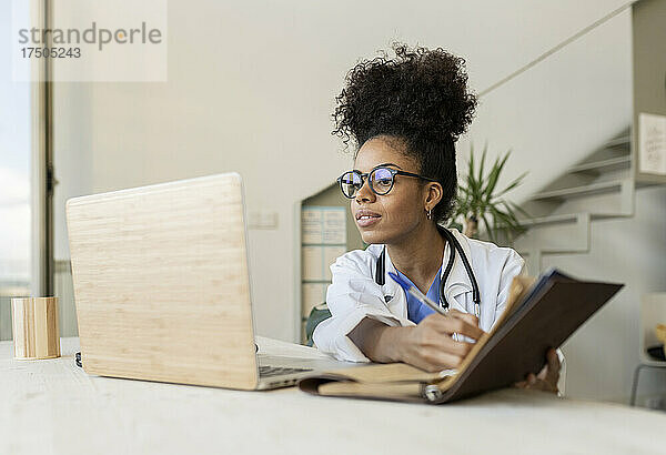 Arzt nimmt an Videoanruf über Laptop im Heimbüro teil