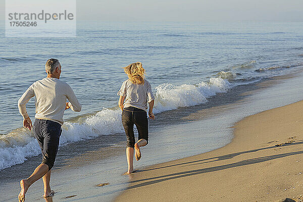 Mann rennt Frau am Strand hinterher