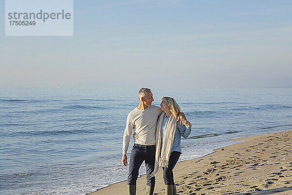 Mann und Frau spazieren gemeinsam am Strand
