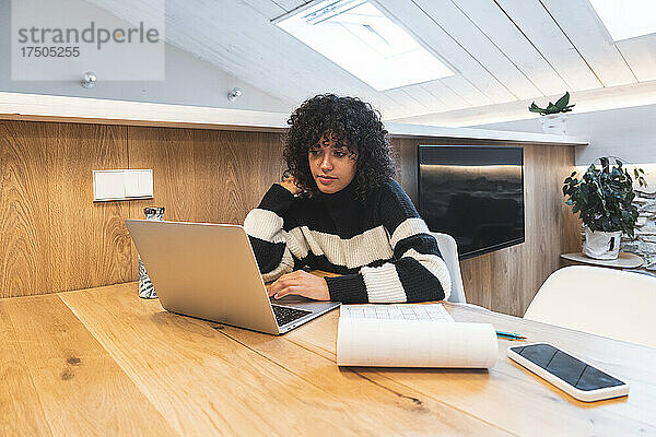 Geschäftsfrau mit lockigem Haar arbeitet im Büro am Laptop