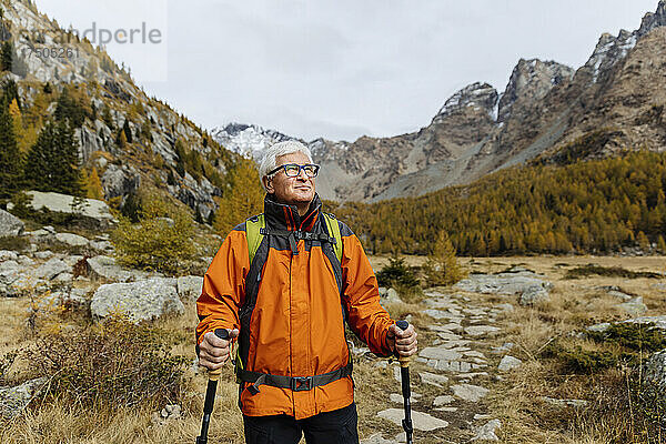Lächelnder Wanderer mit Wanderstöcken auf dem Berg in den Rätischen Alpen  Italien