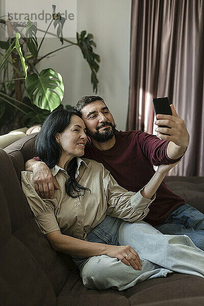 Paar macht Selfie mit dem Handy auf dem Sofa