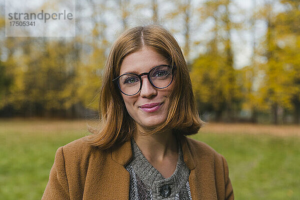 Schöne Frau mit Brille lächelt im Park