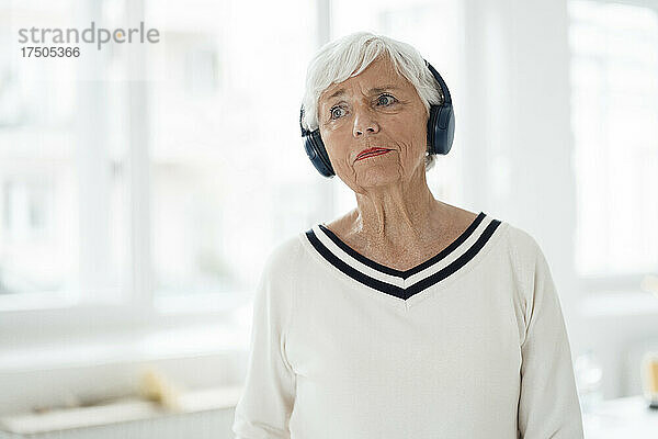 Frau hört zu Hause Musik über kabellose Kopfhörer