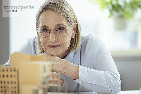 Geschäftsfrau mit Brille betrachtet Model im Büro