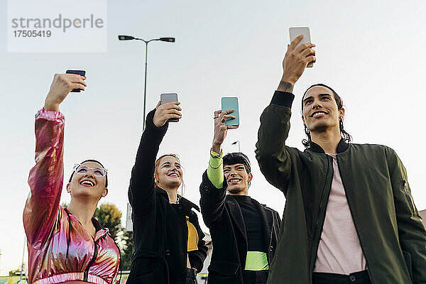 Lächelnde Freunde  die gemeinsam Selfies über Smartphones machen