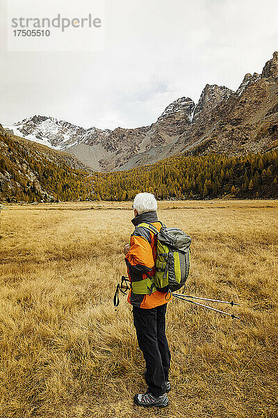Tourist mit Rucksack blickt am Wochenende auf die Berge in den Rätischen Alpen  Italien