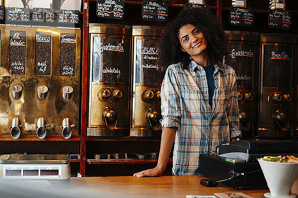 Lächelnder Besitzer steht an der Kasse einer Kaffeerösterei