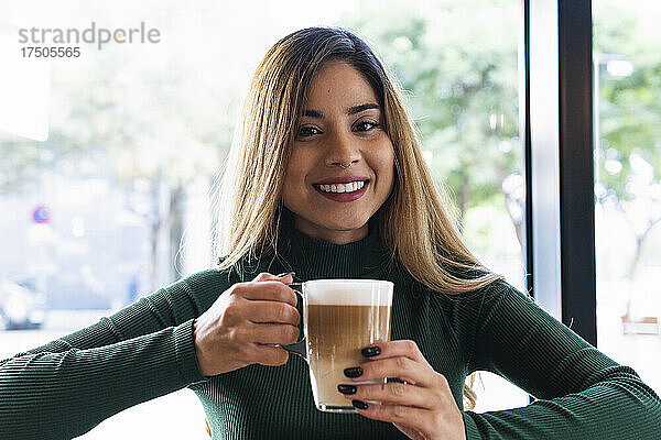 Lächelnde Frau hält Kaffeetasse im Café