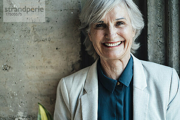 Lächelnde ältere Geschäftsfrau vor der Wand