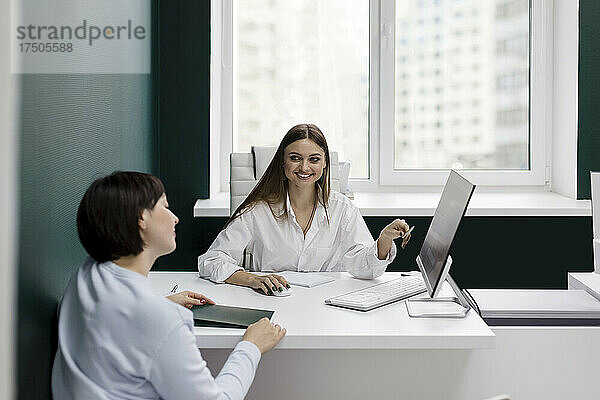 Lächelnde Verkäuferin gestikuliert und schaut den Kunden im Büro an