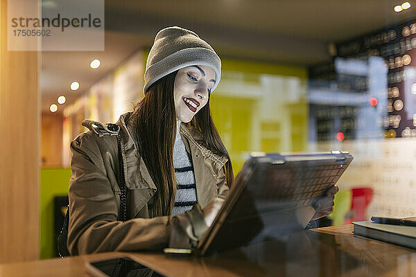 Frau benutzt Touchscreen-Laptop im Café  gesehen durch Glas