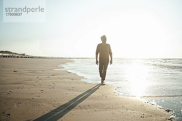 Mann geht am Strand an der Küste entlang
