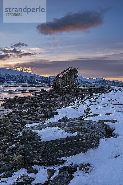 Schiffswrack liegt im Wintermorgen am Ufer des abgelegenen Fjords