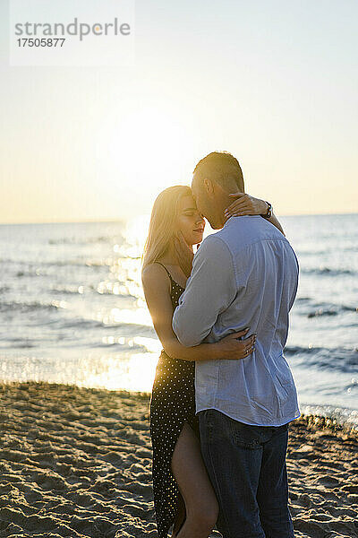 Liebevolles junges Paar umarmt sich am Strand