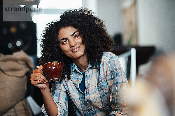 Lächelnde Geschäftsfrau mit Kaffeetasse in der Kaffeerösterei