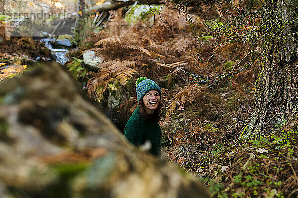 Lächelnde Frau mit Strickmütze im Herbstwald