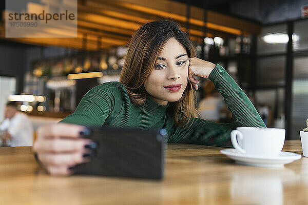 Frau macht Selfie mit Handy am Cafétisch