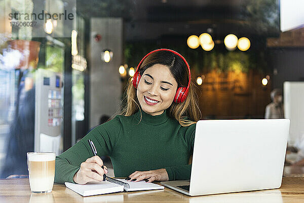 Geschäftsfrau schreibt mit Laptop Tagebuch im Café