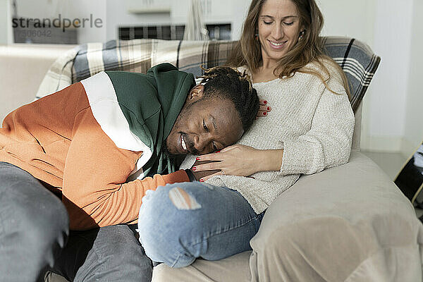 Glücklicher Mann legt den Kopf auf den Bauch einer schwangeren Frau  die zu Hause sitzt