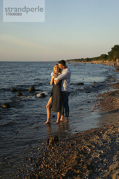 Mann umarmt Frau am Strandufer