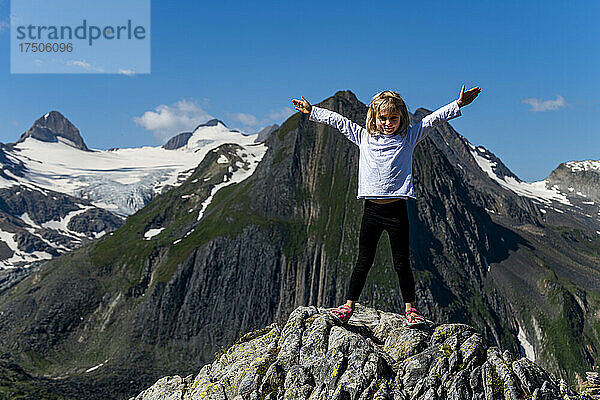 Mädchen mit ausgestreckten Armen steht auf einem Felsen  Nufenenpass  Schweiz