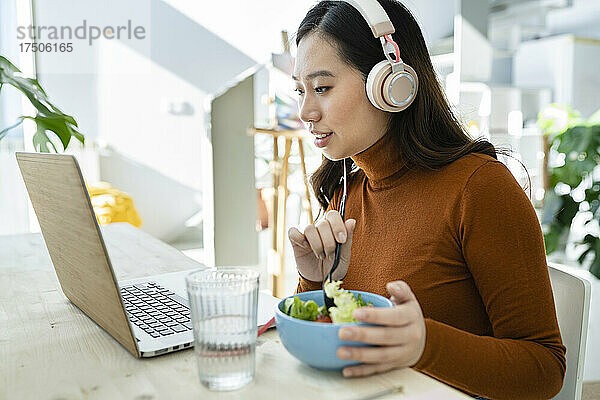 Geschäftsfrau mit Laptop beim Mittagessen am Tisch