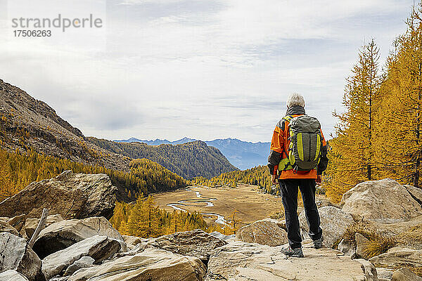 Rucksacktourist steht auf einem Felsen in den Rätischen Alpen  Italien