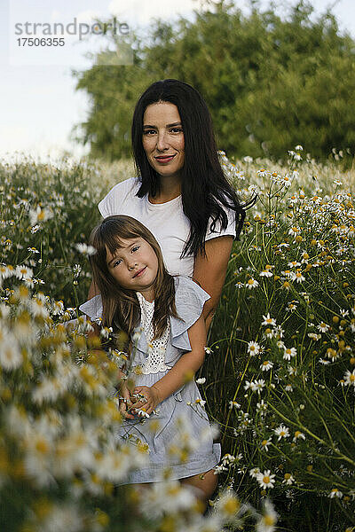 Mutter und Tochter stehen inmitten von Blumen auf der Wiese