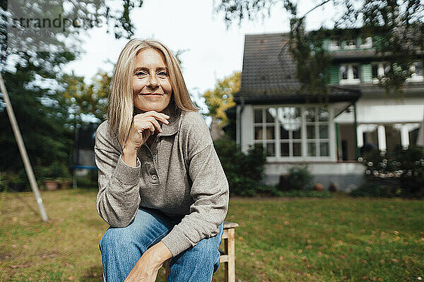 Blonde Frau mit der Hand am Kinn im Hinterhof