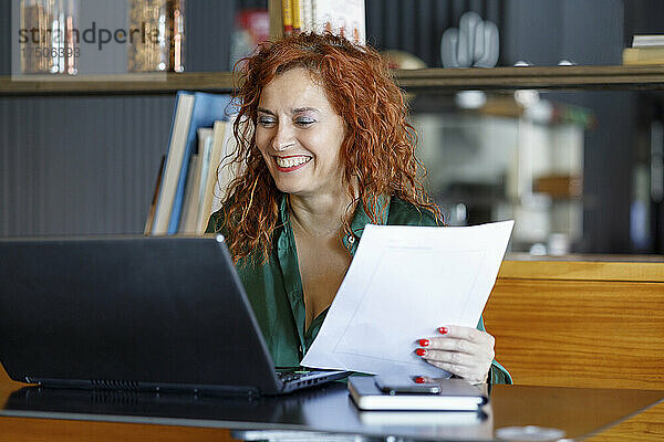 Geschäftsfrau mit Dokument und Laptop am Cafétisch