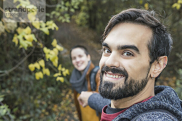 Lächelnder  gutaussehender Mann mit Freundin beim Wandern im Wald