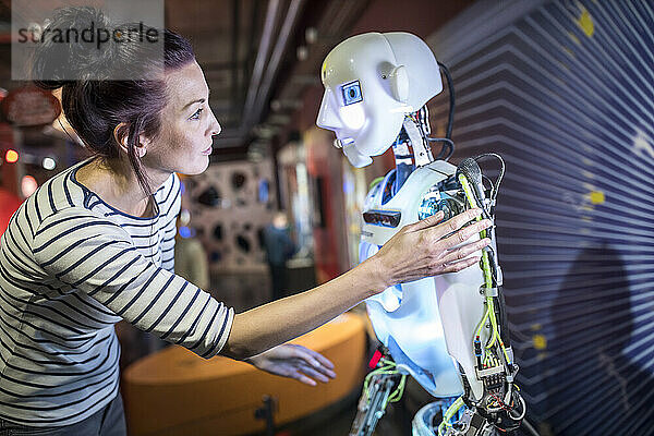 Techniker gestikuliert in der Nähe eines menschlichen Roboters in der Werkstatt
