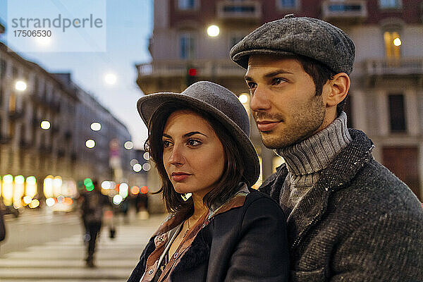 Selbstbewusstes junges Paar mit Hut schaut in der Stadt weg