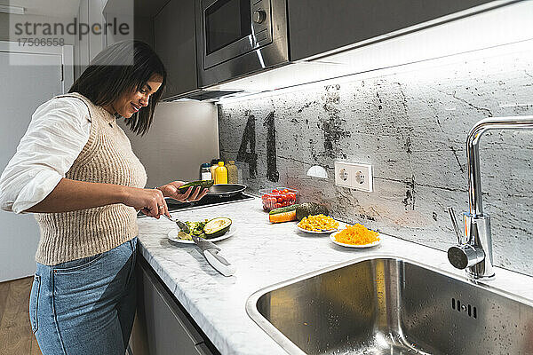 Junge Frau bereitet zu Hause in der Küche Poke mit Avocado zu