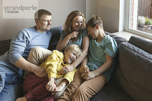 Mann blickt Familie lachend auf Sofa an