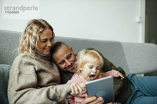 Glückliche Familie nutzt Tablet-PC auf dem Sofa zu Hause